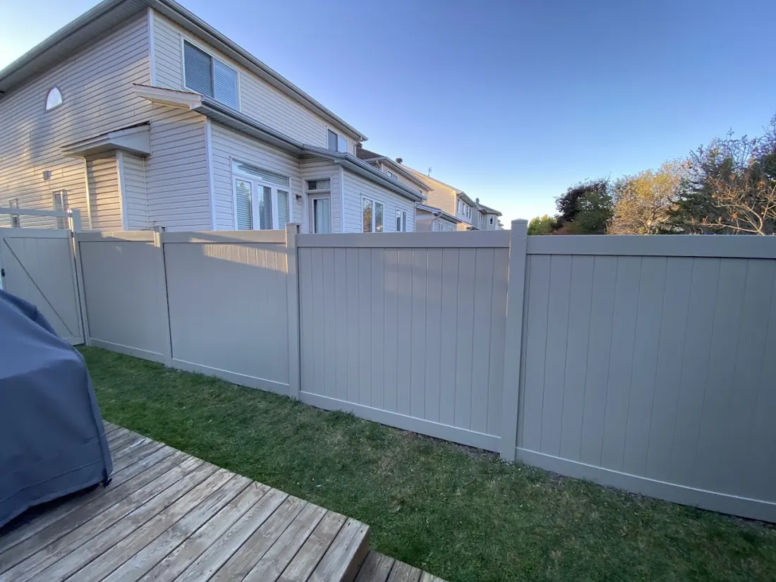 Taupe vinyl privacy fence beside a wooden deck in a Stittsville backyard
